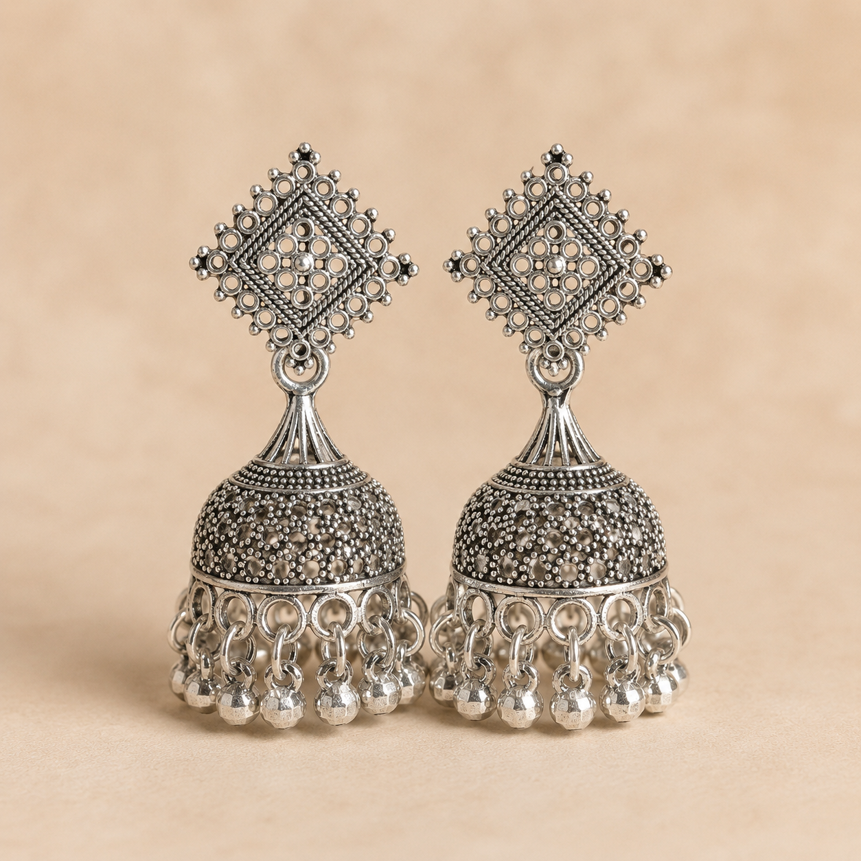 Handcrafted oxidized silver jhumka earrings with intricate filigree square stud design and dangling ghungroo beads by Shining Riva